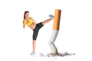 Photo of an athletic woman kicking a giant cigarette butt