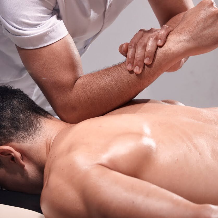 focused-shoulder-blade-remedial-massage-session A detailed view of a focused remedial massage therapy session on the shoulder blade, where a therapist's hands skillfully work to relieve muscle tension in a client's upper back.