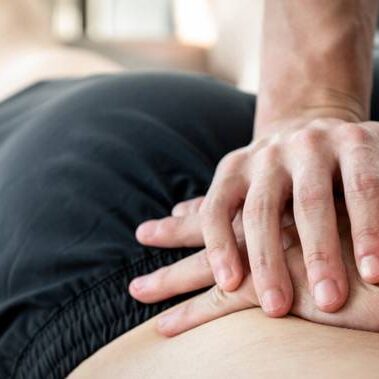 Therapist giving lower back sports massage to athlete male patient in clinic