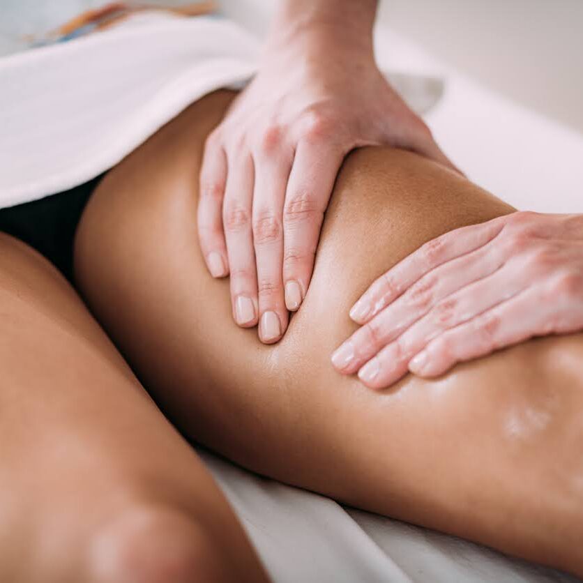 Close-up of a sports massage therapist's hands applying a thigh massage technique.